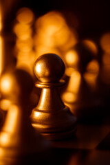 Poster - Vertical closeup shot of metal chessmen pawn on a board illuminated with bright light