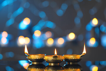 Wall Mural - Lit diyas on table against blurred lights. Diwali lamps