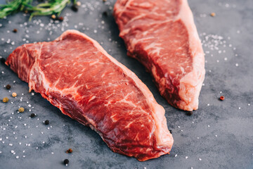 Wall Mural - Raw New York striploin beef steak isolated on gray background with rosemary and spices