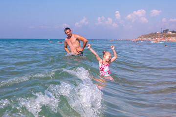 Dad and child are having fun at sea. Father and daughter on the beach on a sunny day.