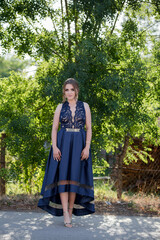 Poster - Caucasian female from Bosnia and Herzegovina in an elegant blue dress with trees in the background