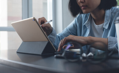 Poster - Casual business woman working on digital tablet and laptop computer at home office