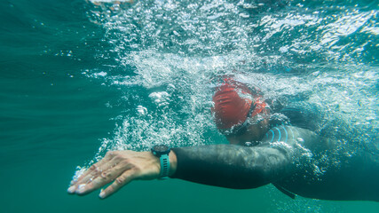 Wall Mural - Athlete in a wetsuit swims in open water