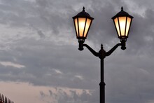 Street Lamp With Lamps On Against A Background Of Dark Clouds At Dusk.