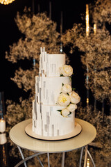 White-pink beautiful wedding cake on the background of the evening wedding arch