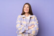 © luismolinero - Teenager caucasian girl isolated on purple background looking up while smiling