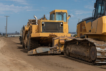 Heavy grading equipment vehicles lined up on open dirt field in California farmland ready for a day of work.