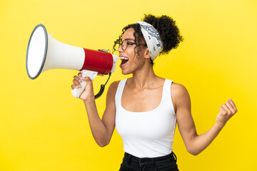 Wall Mural - Young african american woman isolated on yellow background shouting through a megaphone to announce something in lateral position