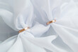 White cloth is threaded through the two golden wedding rings.