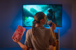 © Anton - A girl with popcorn and a drink sits in the room and watches TV. Night time. Insomnia, watching your favorite movie, loneliness, leisure. Shooting from the back.