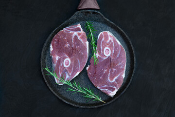 Raw lamb steaks and herbs on a pan