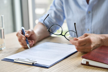 Wall Mural - Businesswoman lawyer reading trust partnership contract sit at table in office holding glasses in hand. Executive ceo checking legal bank sale financial investment agreement. Close up.