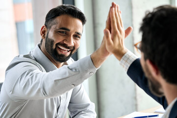 Wall Mural - Indian happy smiling multiracial professional ceo businessman giving highfive to business partner after financial acquisition bank bargain contract at office. High five concept. Over shoulder view.