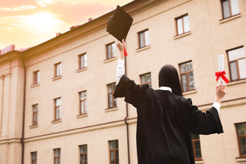 Poster - Student with diploma after graduation ceremony outdoors, back view. Space for text