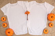 Two White Baby Bodysuit Mockup With Halloween Decor On Gold Background. Autumn, Halloween And Thanksgiving Concept