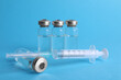 © New Africa - Disposable syringe with needle and vials on light blue background