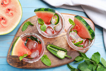 Glasses of spicy cocktail with jalapeno and mint on light blue wooden table, flat lay