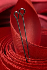 two sewing pins on the background of a red cloth tape. close-up.