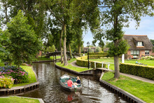 Sailing Through The Giethoorn Canal With Picturesque Houses On Small Islands, Narrow Wooden Bridges And Beautiful Vegetation, Giethoorn, Netherlands