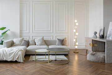 minimalistic interior of an ultra modern open plan apartment with white and gray walls with a relief and gray stylish upholstered furniture and huge windows