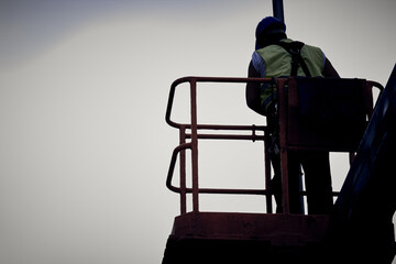 Poster - Manual worker on a telescopic lifter basket fixing street light pole.