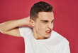 © SHOTPRIME STUDIO - a man with an angry expression holds his hand behind his head white t-shirt Studio red background