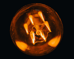 Canvas Print - Closeup of a lit light bulb on a black background