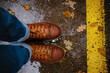 feet of a woman walking along asphalt road in autumn forest in the rain. Pair of shoe on slippery road in the fall. Abstract empty blank of the autumn weather