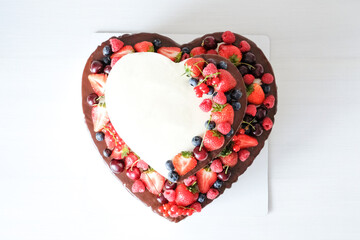 Wall Mural - Valentine cake in form of heart with whipped pink cream, decorated with berries on white background. Top view