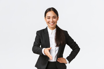 Wall Mural - Confident smiling asian businesswoman extend hand for firm handshake, greeting client or business partner to sign deal, looking determined and ready, standing white background