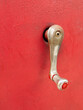AN OLD CRANK - old crank handle against weathered red surface, vintage gas pump 