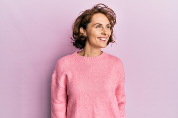 Wall Mural - Young brunette woman wearing casual winter sweater looking to side, relax profile pose with natural face and confident smile.