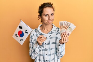 Poster - Young brunette woman holding south korean won banknotes skeptic and nervous, frowning upset because of problem. negative person.