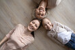 © fizkes - Top view portrait of smiling three generations of Caucasian women lying on wooden floor have fun relax together. Happy little girl child with young mother and old grandmother play show family unity.