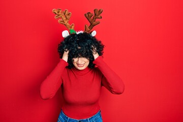 Poster - Young middle east woman wearing cute christmas reindeer horns suffering from headache desperate and stressed because pain and migraine. hands on head.