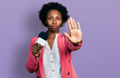 © Krakenimages.com - African american woman with afro hair holding reporter microphone with open hand doing stop sign with serious and confident expression, defense gesture