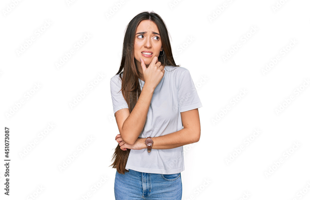 Young hispanic girl wearing casual white t shirt thinking worried about a question, concerned and nervous with hand on chin