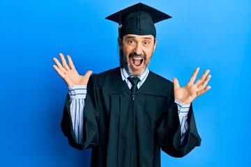 Poster - Middle age hispanic man wearing graduation cap and ceremony robe celebrating crazy and amazed for success with arms raised and open eyes screaming excited. winner concept