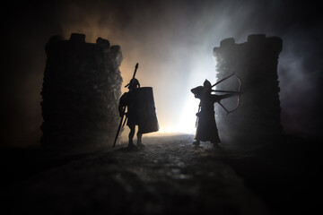 Wall Mural - Medieval battle scene. Silhouettes of figures as separate objects, fight between warriors at night. Creative artwork decoration. Foggy background.