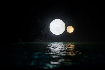 Wall Mural - Romantic and scenic panorama with full moon on sea to night. Table decoration with moon miniature and water.