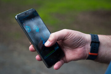 Christchurch, Canterbury, New Zealand, September 2 2019: A man plays Ingress, an augmented reality game on his cellphone in a park in Christchurch, New Zealand