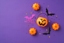 Top View Photo Of Halloween Decorations Pumpkins Basket Black Sequins Golden Stars Bat Silhouettes And Purple Inscription Happy Halloween On Isolated Violet Background With Copyspace