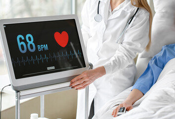 Wall Mural - Female doctor with heart rate monitor near patient in clinic