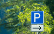 Parking lot, right direction parking sign with green leaves in the background.