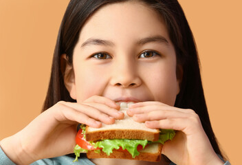 Canvas Print - Little girl eating tasty sandwich on color background, closeup