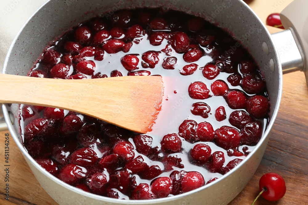 Preparing of tasty cherry jam on color background, closeup