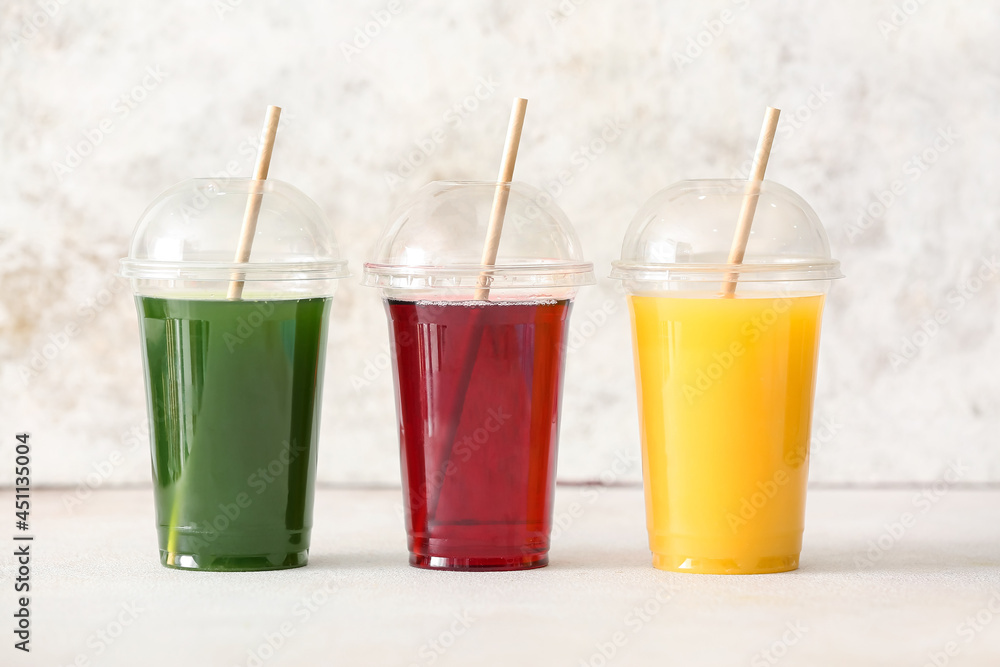Plastic cups with healthy juice on light background