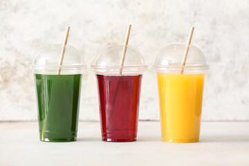 Plastic cups with healthy juice on light background