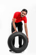 © PRASANNAPIX - Handsome young male mechanic with new tires isolated on white background.