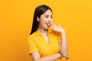 Attractive Beautiful asian woman standing and posing. Sexy female in yellow shirt on isolated yellow background. Charming female smiling.